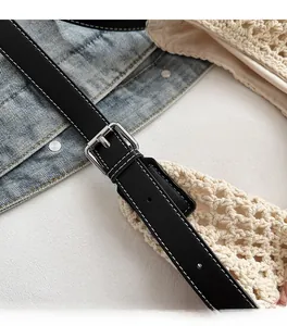 Detail of adjustable black leather strap with white stitching and silver metal buckle