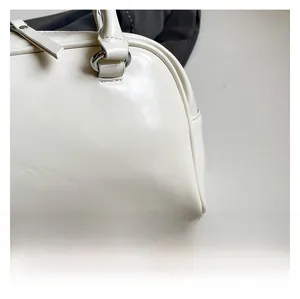 Close-up of white leather texture and silver D-ring hardware on a stylish handbag
