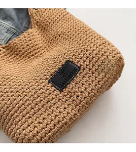 Detailed close-up of khaki woven shoulder bag with cotton crochet texture and leather logo