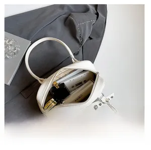 Detail view of large capacity interior for white leather handbag with bowtie rivet