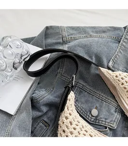 Close-up of cream hollow woven crochet bag with black leather shoulder strap and stitching