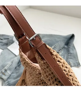 Close-up of woven bag showing brown leather strap with stitching and pink satin lining