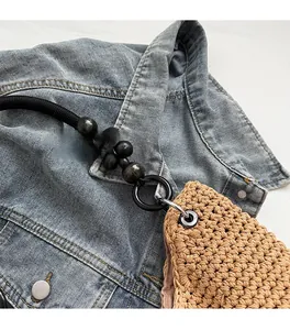 Detailed shot of woven khaki bag featuring dark wooden beads and sturdy black ring hardware