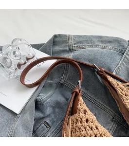 Detail of handwoven khaki beach tote featuring brown leather straps and metal buckles