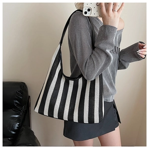 Macro view of vertical striped knit tote bag showing black leather strap and woven texture