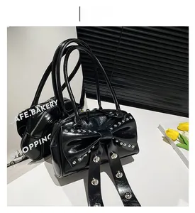 Detail of black ribbon handbag featuring silver studs and glossy patent leather finish