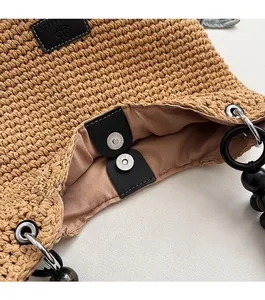 Close-up of woven bucket bag featuring black magnetic clasp and bead handle detail