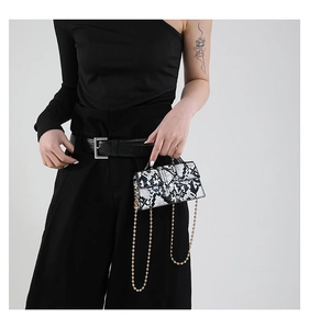 Detail of trendy snakeskin pattern small crossbody bag with delicate gold ball chain