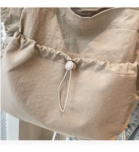 Detail of khaki nylon tote bag showing adjustable drawstring closure and wrinkled fabric texture