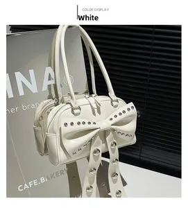 Detail of white glossy leather handbag featuring a large bow and silver rivet studs