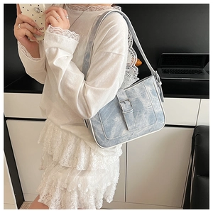 Detail of light blue denim crescent bag with white stitching and silver metal buckle