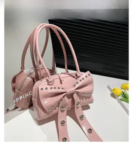 Pink handbag with large rivet bow and glossy patent finish on a mirrored surface