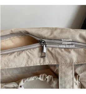 Close-up of a smooth silver zipper and transparent window on a beige fabric tote bag