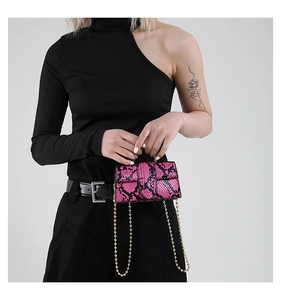 Detail of pink snakeskin pattern bag with round metal handle and gold chain strap