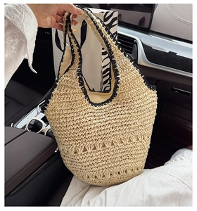 Detail of a beige woven straw tote bag with black trim, perfect for summer beach holidays