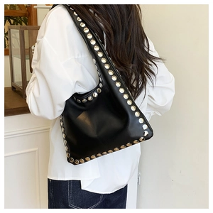 Detailed view of the black faux leather tote with silver rivets on wide shoulder strap