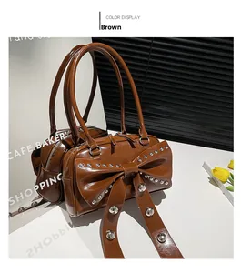 Detail of dark brown glossy patent leather bag with oversized rivet bow and slender handles