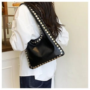 Détail des rivets argentés sur sac hobo noir en cuir porté comme sac sous le bras