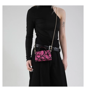 Dettaglio mini borsa pitonata rosa con catena dorata mostrata su una modella