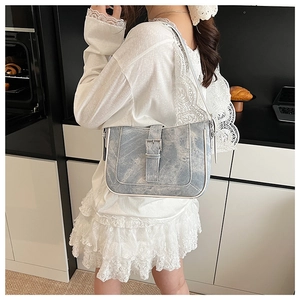 Detail of light blue crescent shoulder bag with silver buckle and white contrast trim