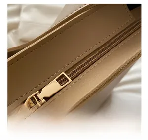 Detail of premium gold metal zipper on a light brown textured leather bucket bag