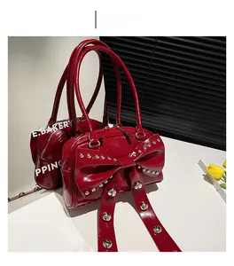 Detail of red patent leather handbag featuring large bow design and metallic rivet accents