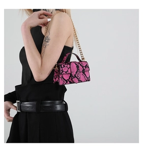 Model showing a pink snakeskin mini handbag with gold chain strap on shoulder