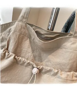 Detail of khaki tote bag showing pleated texture fabric and drawstring adjustment