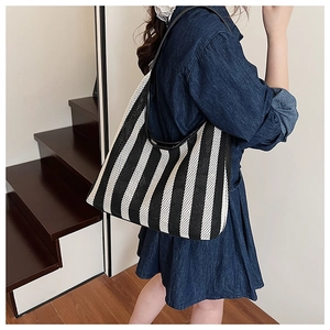 Detail of nautical striped tote bag with woven texture and premium black leather straps