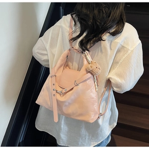 Pink satin finish backpack with striped scarf and brown bear keychain detail view