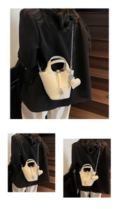 White lychee leather bucket bag with silver chain strap and heart charm on wooden stairs