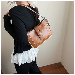 Close-up of brown crescent shoulder bag with white contrast edge and metal buckle