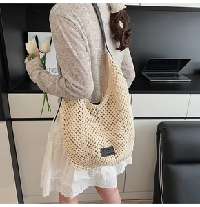 Detail of cream crochet hobo bag with black straps and logo patch shown on model