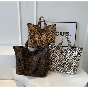 Three large leopard print tote bags in brown and white canvas displayed on white steps