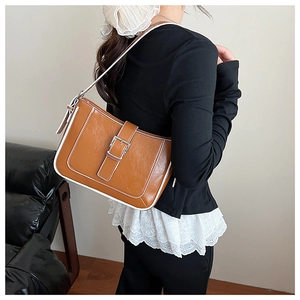 Close-up of brown crescent bag with white piping detail and silver buckle clasp