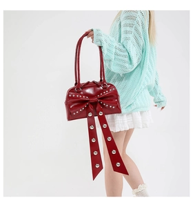 Detail of red bow handbag with silver studs and glossy patent leather finish