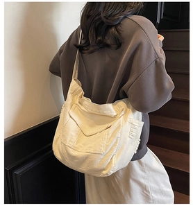 Close-up of beige canvas shoulder bag featuring frayed edge details and minimalist design
