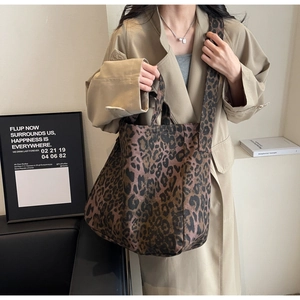 Detailed view of the leopard print canvas tote bag with wide shoulder strap worn by model