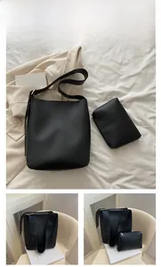Detail of minimalist black bucket bag set with matching zipper pouch in matte faux leather