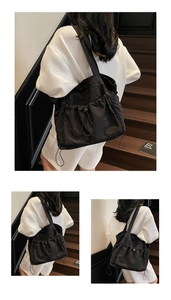 Detail view of black drawstring tote bag made of lightweight wrinkled nylon fabric