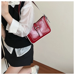 Detail of red glossy leather crescent bag featuring white trim and silver buckle design