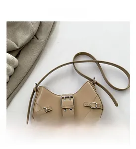 Close-up of beige crescent bag with silver buckles and rivets on herringbone fabric