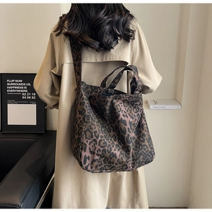 Leopard print canvas tote bag shown worn over the shoulder in a minimalist room