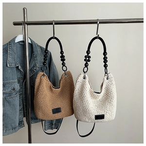 Detail of woven bucket bags with beaded handles in brown and beige tones on hangers