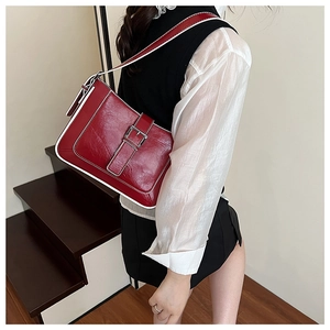 Detail of dark red crescent shoulder bag with white piping and silver buckle hardware