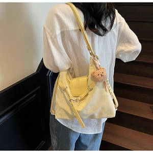 Detail of pale yellow PU leather tote with a cute brown plush bear charm on its side
