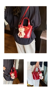 Dettaglio della borsa a secchiello rossa lucida con fibbia in metallo e orsetto peluche