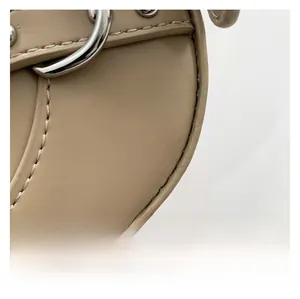 Macro shot of precise stitching and silver metal buckle on the beige leather crescent bag