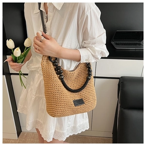 Detail of hand-woven straw shoulder bag with beaded strap and leather logo patch