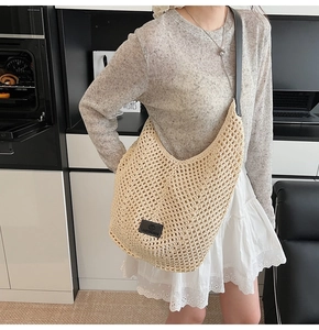 Détail d'un sac demi-lune en crochet fait main de couleur crème avec une bandoulière noire